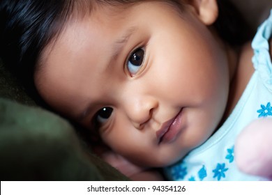 Hispanic Girl Resting Her Head On A Pillow, With A Subtle Smile