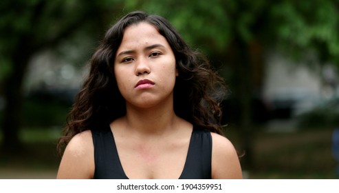 Hispanic Girl Standing Outside Looking At Camera. Latina Young Woman Serious Expression