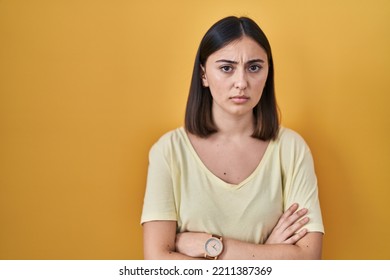 Hispanic girl wearing casual t shirt over yellow background skeptic and nervous, disapproving expression on face with crossed arms. negative person.  - Shutterstock ID 2211387369