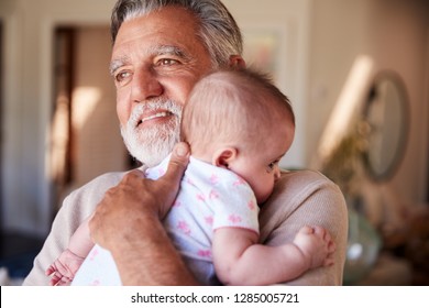 Hispanic grandfather holding his baby grandson, head and shoulders, close up