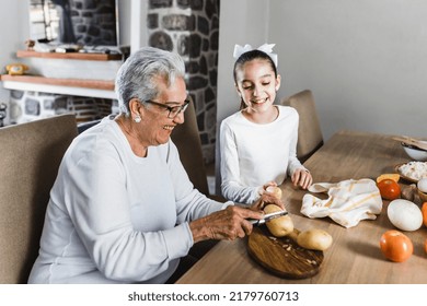 Hispanic Grandmother And Granddaughter Cooking At Home In Mexico Latin America