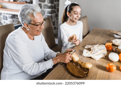 Hispanic Grandmother And Granddaughter Peeling Potatoes And Cooking At Home In Mexico Latin America