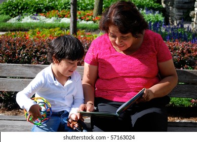 A Hispanic Grandmother And Grandson Reading A Book Together