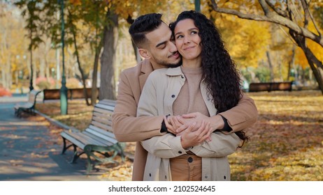 Hispanic Guy Hugs Girlfriend From Back Couple In Love Have Fun Communicating Looking In Distance Discuss Joint Future In Autumn Park Young Family Embracing Feeling Happy Outdoors Romantic Date Concept