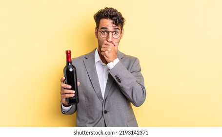 Hispanic Handsome Man Covering Mouth With Hands With A Shocked. Wine Bottle Concept