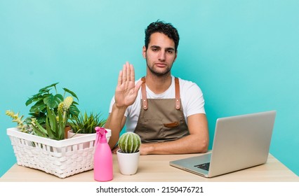 Hispanic Handsome Man Looking Serious Showing Open Palm Making Stop Gesture. Garden And Plants Concept