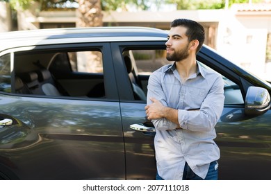 Hispanic Happy Man Leaning On His New Car And Laughing During A Beautiful Day Outside