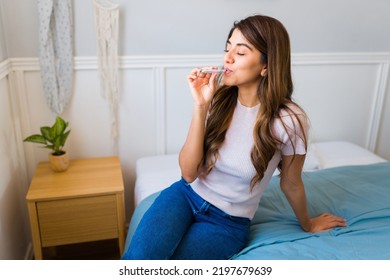 Hispanic Happy Woman Sitting On Her Bed And Relaxing While Smoking Weed Joint To Feel Relaxed 