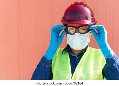 Hispanic Heavy Industry Worker Wearing Protective Mask And Putting On Safety Goggles