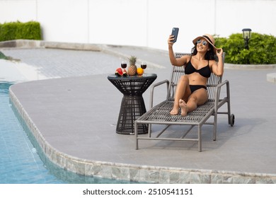 Hispanic latin Woman taking selfie poolside at luxury resort by swimming pool on summer holiday vacation. sunbathing wellness Lifestyle - Powered by Shutterstock