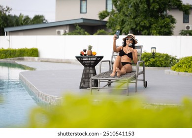 Hispanic latin Woman taking selfie poolside at luxury resort by swimming pool on summer holiday vacation. sunbathing wellness Lifestyle - Powered by Shutterstock