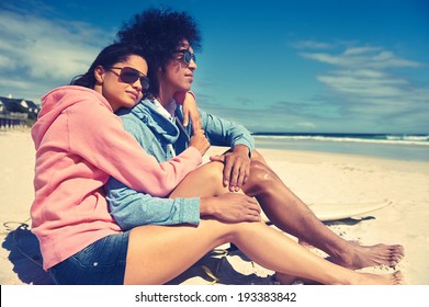 Hispanic Latino couple sitting on beach together in love and affection