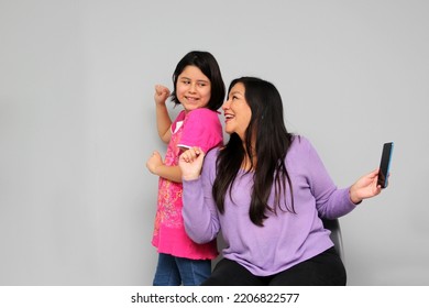 Hispanic Latino Mom And Daughter Play, Dance, Surprise, Enjoy, Taking Selfies Using The Cell Phone Spending Quality Family Time