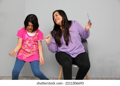 Hispanic Latino Mom And Daughter Play, Dance, Surprise, Enjoy, Taking Selfies Using The Cell Phone Spending Quality Family Time