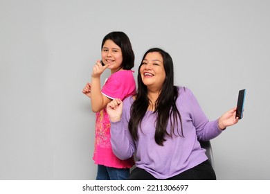 Hispanic Latino Mom And Daughter Play, Dance, Surprise, Enjoy, Taking Selfies Using The Cell Phone Spending Quality Family Time