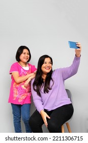 Hispanic Latino Mom And Daughter Play, Dance, Surprise, Enjoy, Taking Selfies Using The Cell Phone Spending Quality Family Time