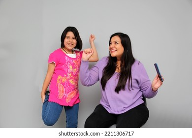 Hispanic Latino Mom And Daughter Play, Dance, Surprise, Enjoy, Taking Selfies Using The Cell Phone Spending Quality Family Time