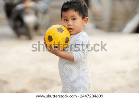 Hispanic little boy playing with a ball in the yard of his house - Boy spending time outdoors - Latin boy with a yellow ball