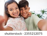 Hispanic little siblings taking a selfie at home - preschool girl and elementary school boy happy siblings social media