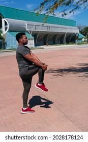 Hispanic Male Athlete Stretching In Park