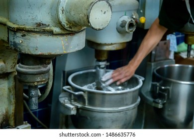 Hispanic Male Blue Collar Worker Is Using An Industrial Stand Mixer To Create Delicious Pastries For His Bakery Shop. The Steel Machine Helps With High-end  Production Of Food For Customers