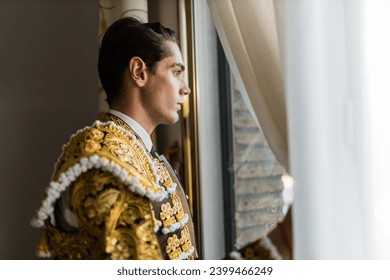 Hispanic male bullfighter looking out window