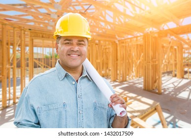 Hispanic Male Contractor with Blueprint Plans Wearing Hard Hat At Construction Site.