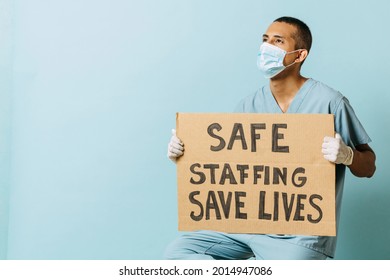 Hispanic Male Doctor Wearing Mask Holds A Banner. A Latin American Man Holds A Banner. Health Concept.