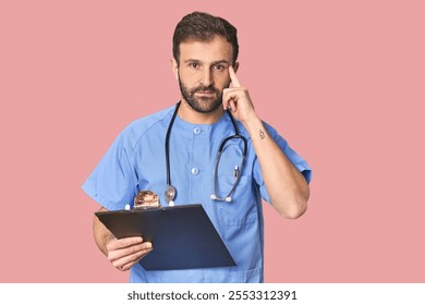 Hispanic male nurse with inventory pointing temple with finger, thinking, focused on a task. - Powered by Shutterstock