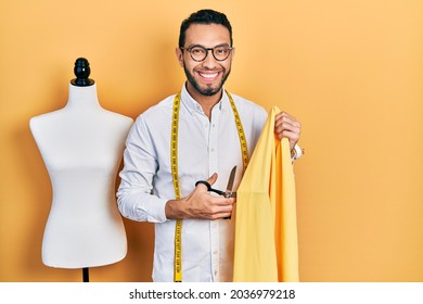 Hispanic man with beard dressmaker designer holding scissors and cloth smiling with a happy and cool smile on face. showing teeth.  - Powered by Shutterstock