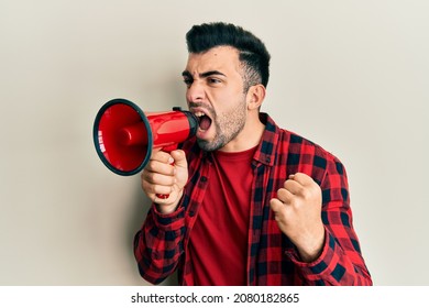 Hispanic man with beard screaming with megaphone - Powered by Shutterstock