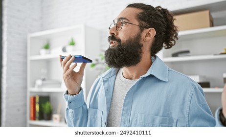 Hispanic man with beard using voice assistant on smartphone in modern office
