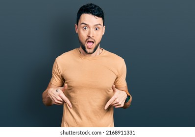 Hispanic Man With Beard Wearing Casual T Shirt Pointing Down With Fingers Showing Advertisement, Surprised Face And Open Mouth 