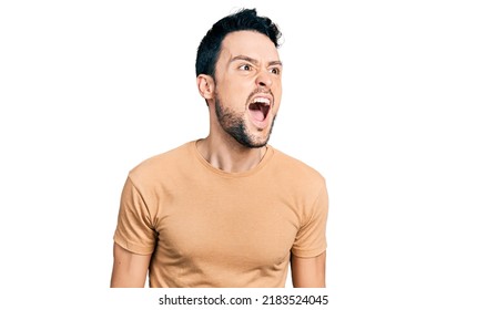 Hispanic man with beard wearing casual t shirt angry and mad screaming frustrated and furious, shouting with anger. rage and aggressive concept.  - Shutterstock ID 2183524045
