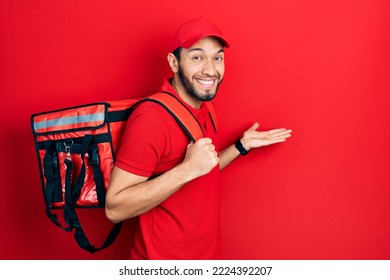 Hispanic Man With Beard Wearing Delivery Package Backpack Celebrating Achievement With Happy Smile And Winner Expression With Raised Hand 