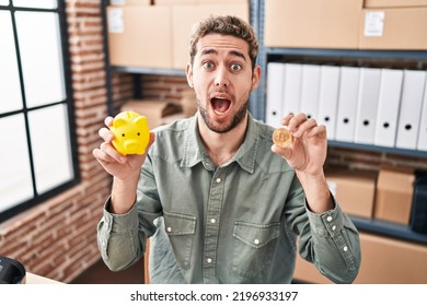 Hispanic Man With Beard Working At Small Business Ecommerce Holding Piggy Bank And Bitcoin Afraid And Shocked With Surprise And Amazed Expression, Fear And Excited Face. 