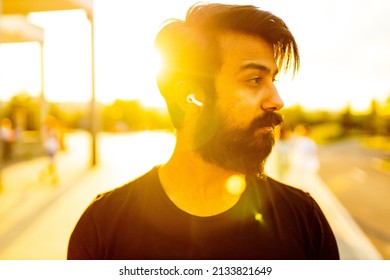 hispanic man in black cotton t-shirt listening a music with earpod in summer park outdoor golden lights