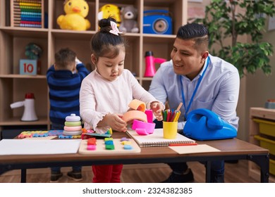 Hispanic man with boy and girl playing with construction blocks sitting on table at kindergarten - Shutterstock ID 2324382385