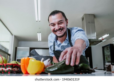 Hispanic Man Cooking At Home Preparing Salad Or Mexican Sauce In Kitchen At Home In Mexico City