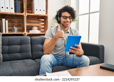 Hispanic man with curly hair doing online session at consultation office smiling happy and positive, thumb up doing excellent and approval sign  - Shutterstock ID 2214295137
