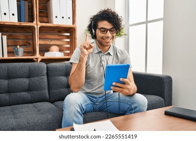 Hispanic man with curly hair doing online session at consultation office smiling with an idea or question pointing finger with happy face, number one  - Shutterstock ID 2265551419