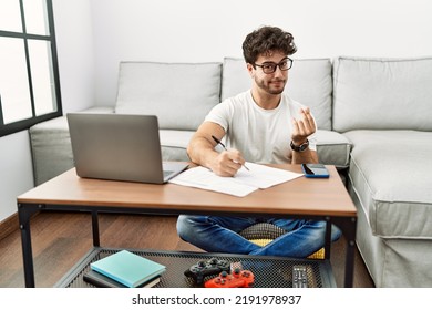 Hispanic Man Doing Papers At Home Doing Money Gesture With Hands, Asking For Salary Payment, Millionaire Business 