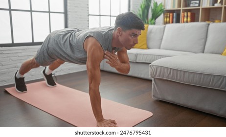 Hispanic man doing push-ups on a mat in a modern living room, showcasing fitness and a healthy lifestyle at home. - Powered by Shutterstock