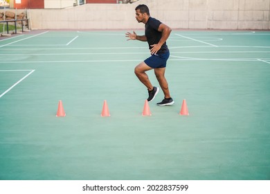 Hispanic Man Doing Speed And Agility Cone Drills Workout Session Outdoors - Focus On Man Face