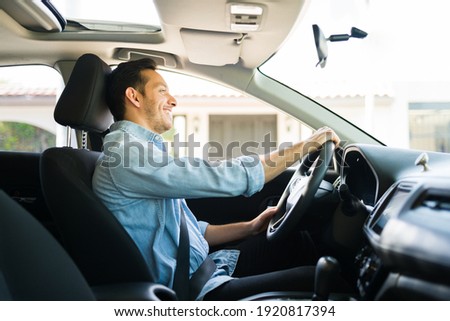 Hispanic man feeling happy while working as a taxi driver on a car sharing service of a mobile app. Happy guy driving a car during the day