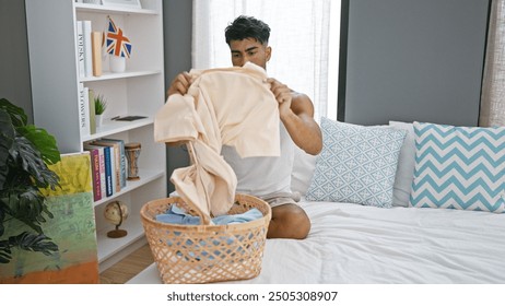 Hispanic man folding laundry in a modern bedroom with decorative pillows and bookshelf. - Powered by Shutterstock