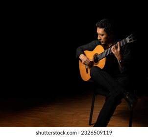 hispanic man playing guitar, guitarist on a black background studio shot, latin professional guitar player