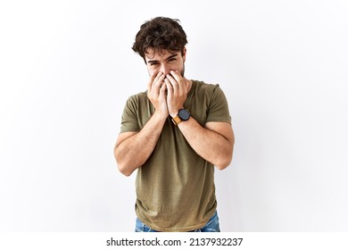 Hispanic man standing over isolated white background laughing and embarrassed giggle covering mouth with hands, gossip and scandal concept 