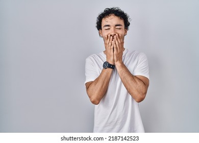 Hispanic Man Standing Over Isolated Background Laughing And Embarrassed Giggle Covering Mouth With Hands, Gossip And Scandal Concept 