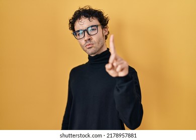 Hispanic Man Standing Over Yellow Background Pointing With Finger Up And Angry Expression, Showing No Gesture 